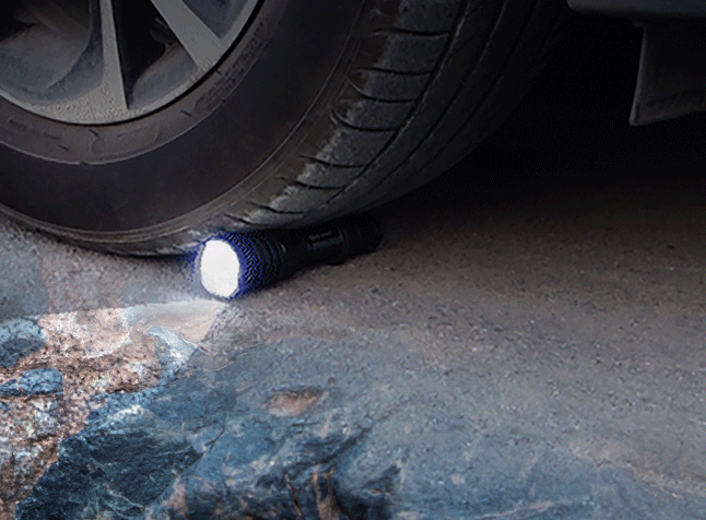 Durable, impact-resistant flashlight crushed by a car tire, still shining. Proves extreme toughness for rugged use & emergency preparedness.