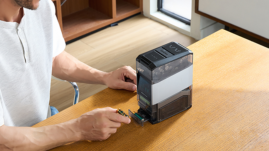 A man using a smart AA and AAA battery charger and organizer station on a wooden desk
