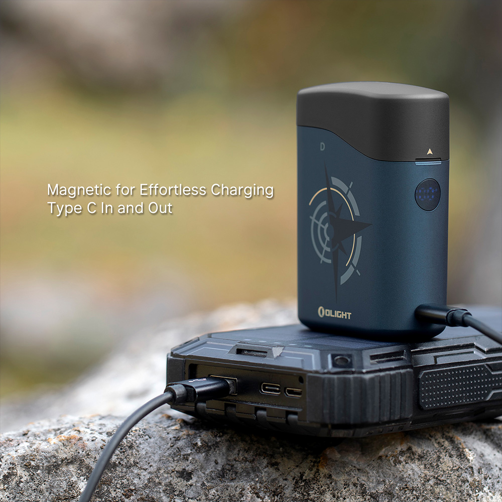 Olight portable device with magnetic charging and Type-C input/output, shown charging from a rugged power bank outdoors for camping and adventure gear.
